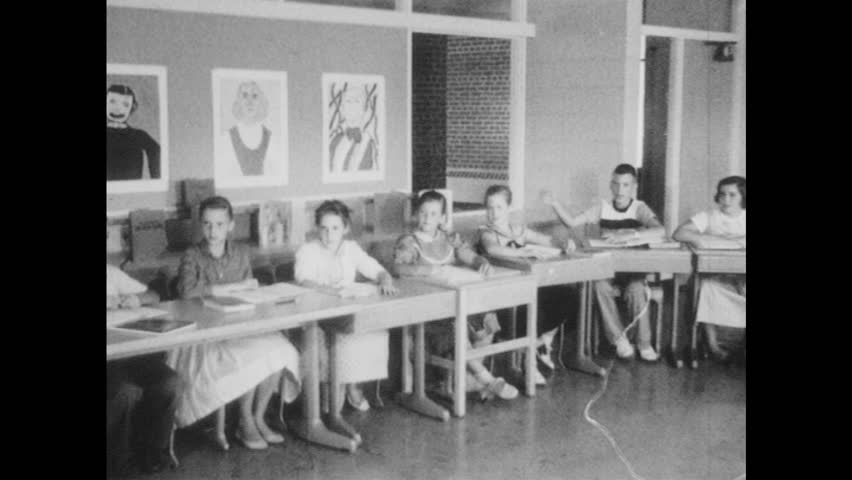 Students Sit At Desks In Classroom Raise Hands Talk Whiteboard