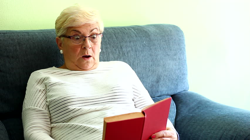 Elder Blonde Hair Lady With Eyeglasses Scared Reading Thriller Book