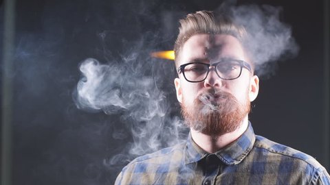 Attractive man exhaling smoke from the nose. Man in glasses advertising a hookah. Slow motion