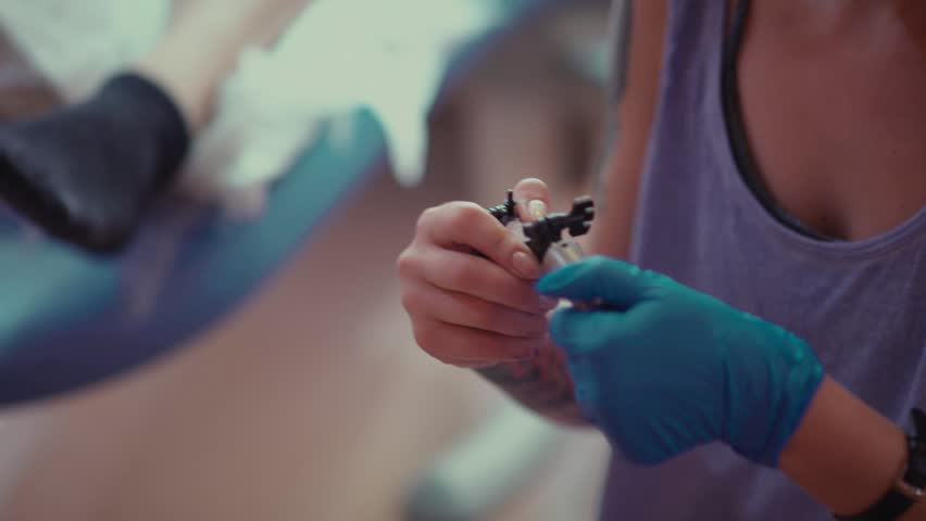 the tattoo artist at work a holding a tattoo machine and the tattoo artist at work a holding a tattoo machine and