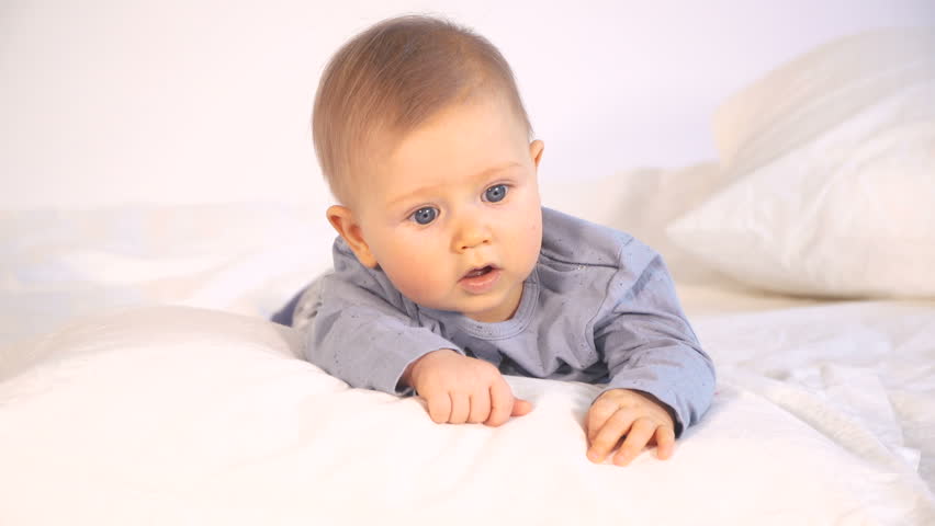 Baby With Big Blue Eyes And Blond Hair In Bed