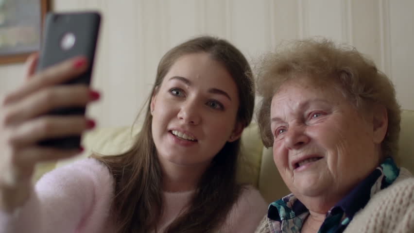 Beautiful Granny And Her Granddaughter Are Doing Selfie Looking At