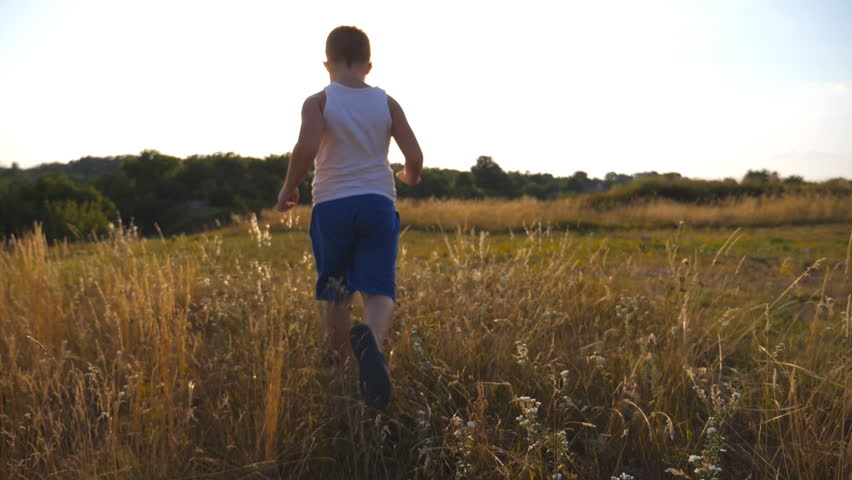 Happy Little Boy Running At Field Behind Camera With Sun Flare At ...