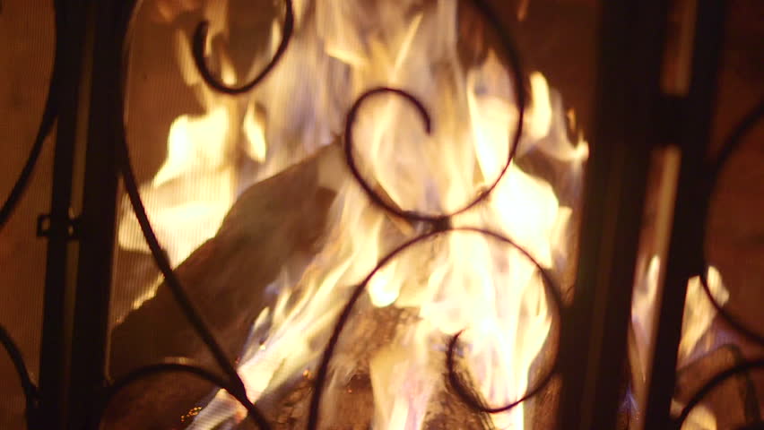 Logs Burning In Vintage Stone Fireplace With Decorative Screen