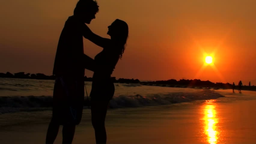 Young Ethnic Couple Silhouette Holding Hands Watching Sunset On Beach ...