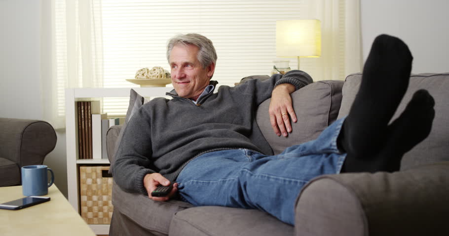 Stock Video Clip of Elderly man watching  tv  on couch  